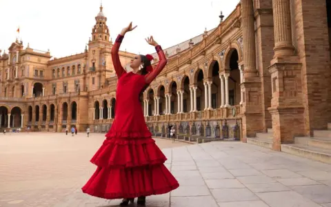 Bailarina flamenca con vestido rojo evoca el origen de las sevillanas en la Plaza de España.