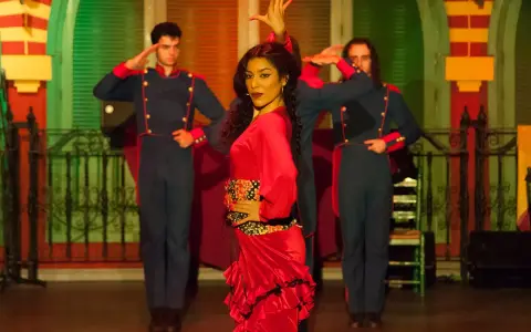 Una bailaora de flamenco con un vestido rojo vibrante, rodeada por dos hombres con uniformes militares, capturando la esencia de las alegrías flamenco.