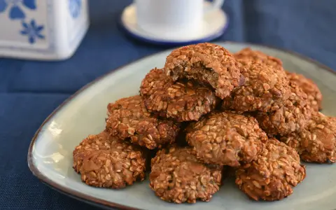 Montón de galletas proteicas caseras en un plato, con una taza de café al fondo. ¡Una deliciosa receta de cookies proteicas!