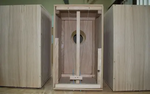 Partes de un cajón de madera, mostrando la estructura interna con cuerdas y un agujero circular.