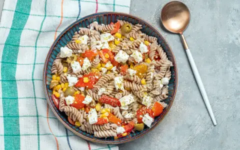 Ensalada de pasta fit con fusilli integral, tomate, maíz, aceitunas y queso feta. Un plato ligero y sabroso.