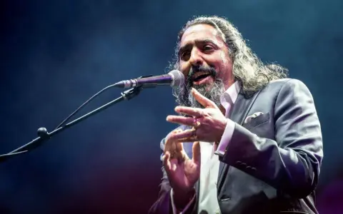 Un cantaor gitano, con su voz profunda y gestos apasionados, cautiva al público en el escenario.