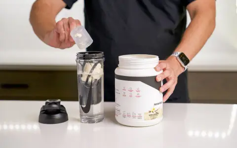 Hombre prepara batido con proteína en polvo para ganar músculo. El envase indica para qué sirve la proteína en polvo: energizar y recuperación post-entreno.