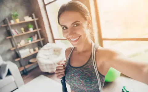 Sonriendo mujer con cuerda de saltar, lista para disfrutar los beneficios de saltar a la comba.