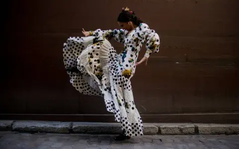 Bailarina de flamenco con vestido de lunares y volantes, capturando la esencia del flamenco origine en un movimiento apasionado.