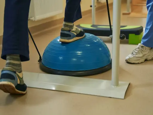Persona practica ejercicios de equilibrio sobre una pelota azul, una forma de como regular el sistema nervioso y mejorar la coordinación.