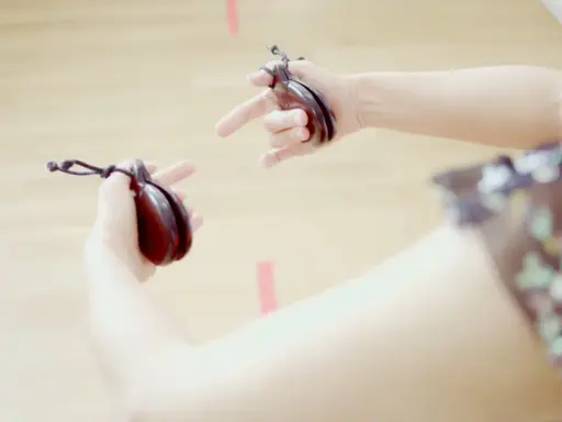 Manos sujetando castañuelas, un instrumento musical tradicional, listas para crear ritmos vibrantes.