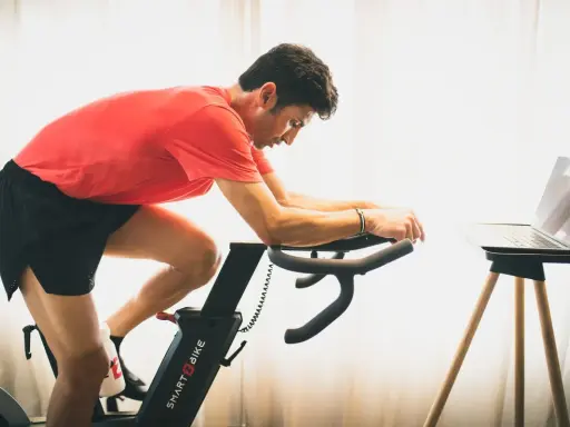 Hombre en bicicleta estática, entrenando para mejorar su artrosis de rodilla.