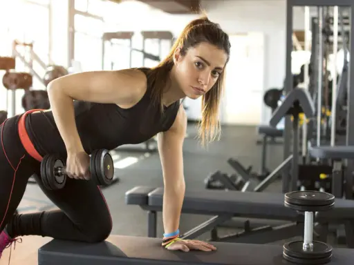 Adolescente de 15 años realizando rutinas de gimnasio con pesas.