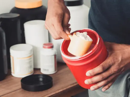 Hombre preparando un batido con suplementos. La creatina aumenta la masa muscular, clave para el entrenamiento.