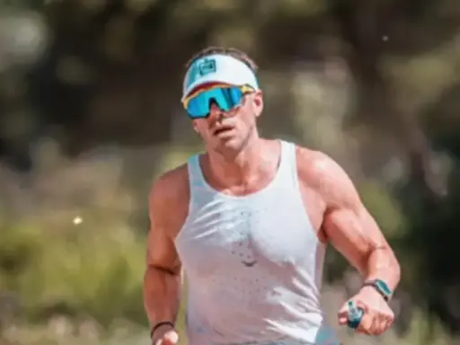 Atleta con gafas deportivas y visera, concentrado en como correr por un sendero.