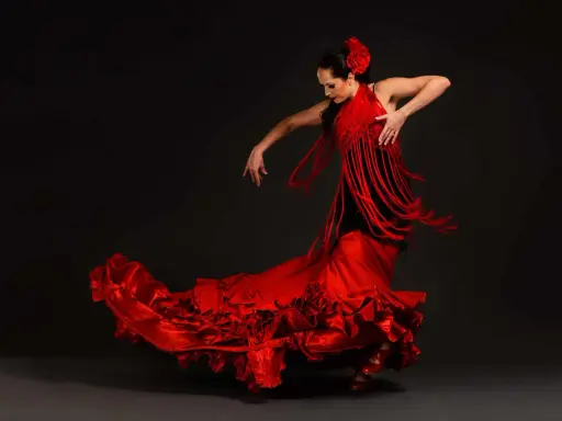 Bailarina de flamenco con vestido rojo voluminoso y mantón de flecos. Un ejemplo de las curiosidades del flamenco, su pasión y elegancia.