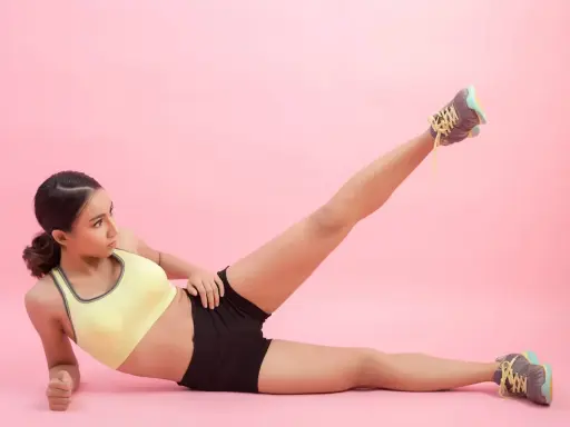 Mujer haciendo ejercicio, levantando una pierna para trabajar el **parte interna del muslo**.