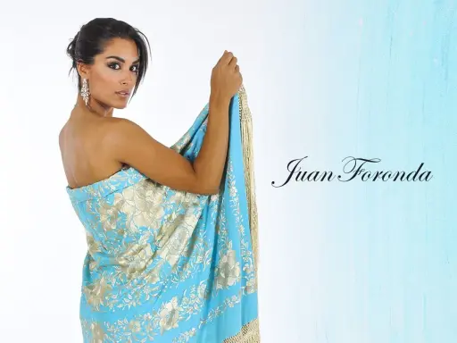 Mujer con mantón de Manila azul turquesa con bordados dorados, mostrando cómo colocar un mantón de manila como vestido.
