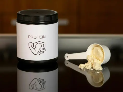 Un bote de proteína y una cuchara con polvo. Ideal para saber como tomar proteína y potenciar tus entrenamientos.