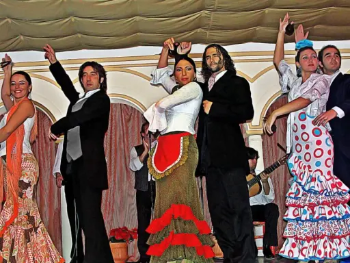 Artistas muestran cómo se bailan las sevillanas con pasión y gracia. Vestidos vibrantes y castañuelas llenan el escenario.
