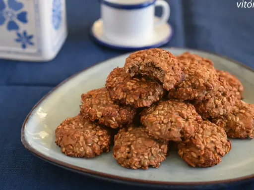 Montón de galletas proteicas caseras en un plato, con una taza de café al fondo. ¡Una deliciosa receta de cookies proteicas!