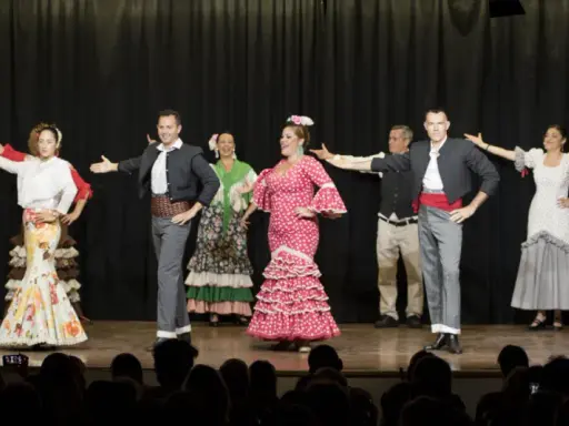 Artistas de sevillanas y flamenco en escena, con trajes coloridos y movimientos apasionados.