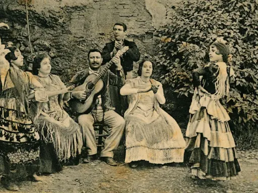 Grupo de músicos y bailarinas, una de ellas realiza un zambra baile gitano, con guitarras y mantones.