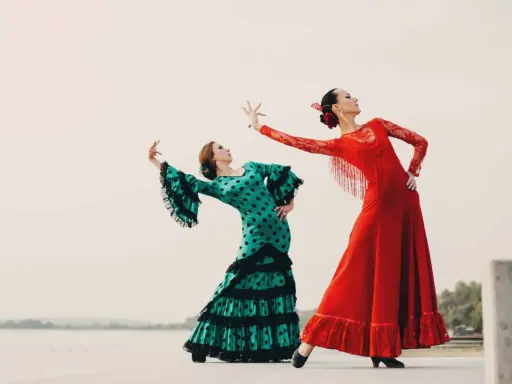 Dos bailarinas de flamenco, una con vestido verde de lunares y otra con rojo vibrante, ejecutan un apasionado flamenco ballo.