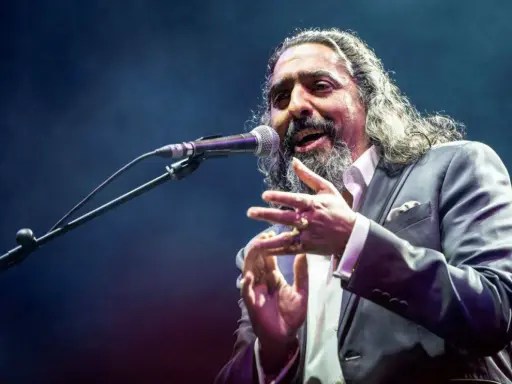 Un cantaor gitano, con su voz profunda y gestos apasionados, cautiva al público en el escenario.