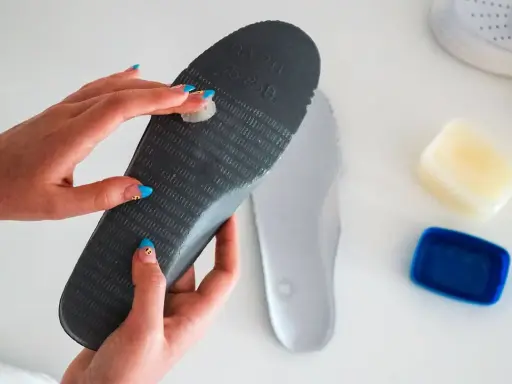 Manos aplicando vaselina en una plantilla para zapatos, un método para como quitar ruido zapatos goma.