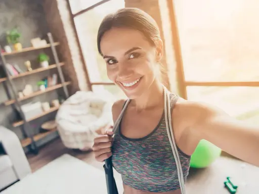 Sonriendo mujer con cuerda de saltar, lista para disfrutar los beneficios de saltar a la comba.