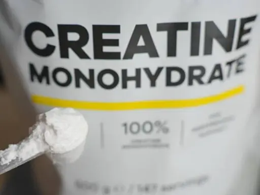 Bolsa de creatina monohidrato con una cuchara llena de polvo blanco. Ideal para potenciar tus músculos.