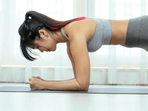 Mujer en posición de plancha, entrenando para tonificar su cuerpo. La pregunta de cuanto se tarda en tonificar el cuerpo mujer es clave para su motivación.