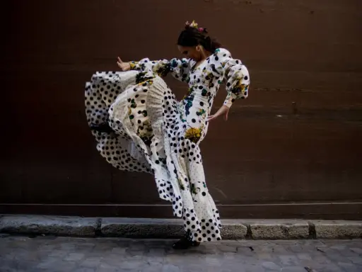 Bailarina de flamenco con vestido de lunares y volantes, capturando la esencia del flamenco origine en un movimiento apasionado.