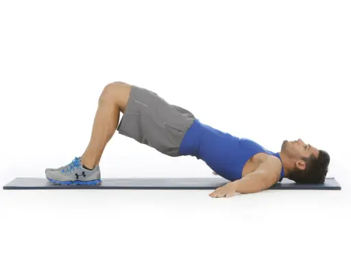Hombre realizando puente de glúteo, un ejercicio clave para fortalecer la zona lumbar en el gym.