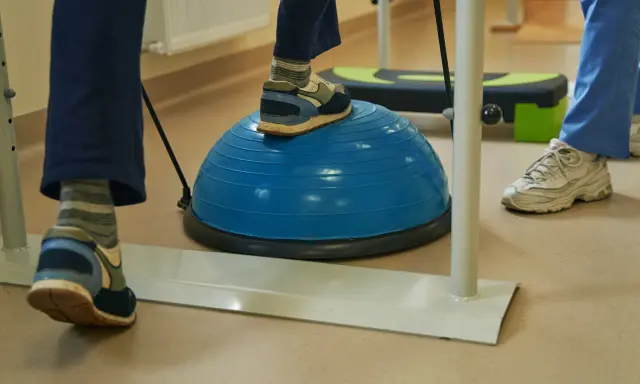 Persona practica ejercicios de equilibrio sobre una pelota azul, una forma de como regular el sistema nervioso y mejorar la coordinación.