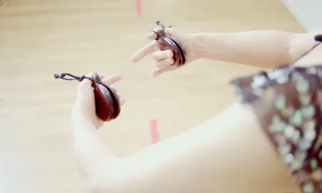 Manos sujetando castañuelas, un instrumento musical tradicional, listas para crear ritmos vibrantes.
