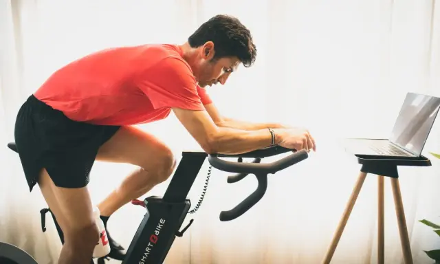 Hombre en bicicleta estática, entrenando para mejorar su artrosis de rodilla.