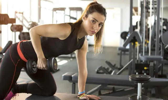 Adolescente de 15 años realizando rutinas de gimnasio con pesas.