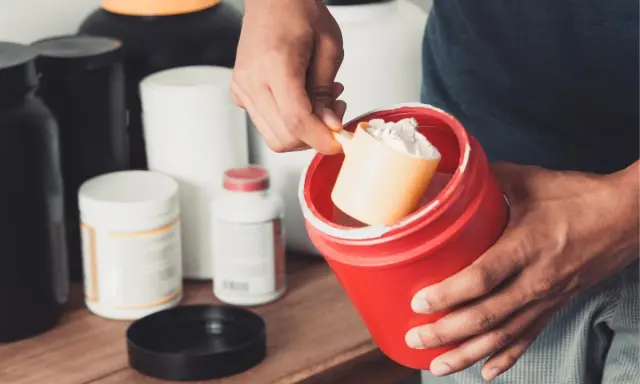 Hombre preparando un batido con suplementos. La creatina aumenta la masa muscular, clave para el entrenamiento.