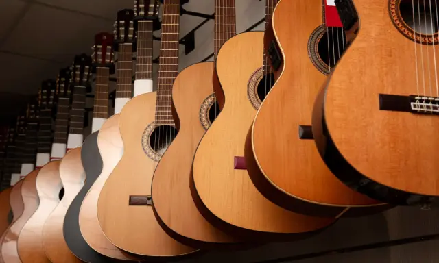 Varias guitarras cuelgan en fila, mostrando la diferencia entre guitarra española y flamenca.