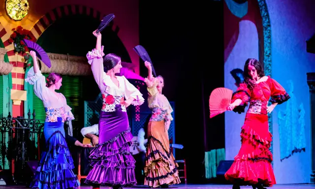 Bailarinas de flamenco con abanicos desplegados, mostrando las partes de un abanico en un espectáculo vibrante.