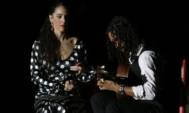 Una bailaora flamenca con vestido de lunares y un guitarrista crean un duende que es pura pasión en la oscuridad.