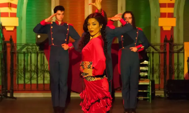 Una bailaora de flamenco con un vestido rojo vibrante, rodeada por dos hombres con uniformes militares, capturando la esencia de las alegrías flamenco.