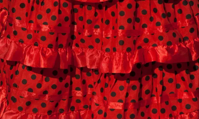 Falda roja con lunares negros, con volantes y cintas, ideal para un baile típico de Sevilla.