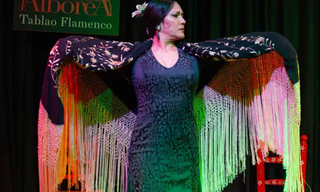 Una bailaora flamenca, con un mantón bordado y flecos de colores, se prepara para su actuación en el tablao Alborea.