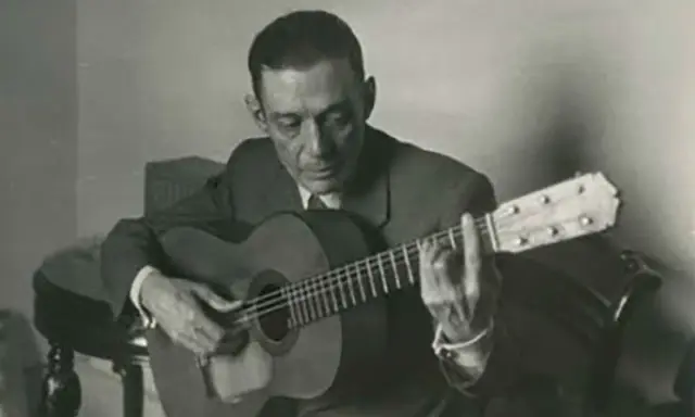 Un guitarrista flamenco andaluz, con traje y corbata, toca su guitarra con pasión.