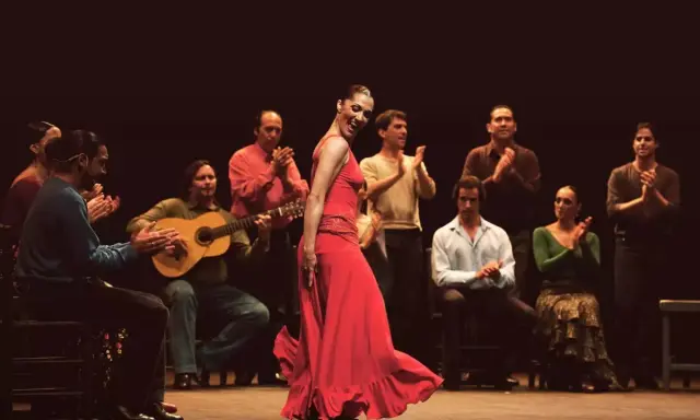 Bailaora flamenca en vestido rojo, acompañada por guitarrista y palmas. Un espectáculo de mejor flamenco.