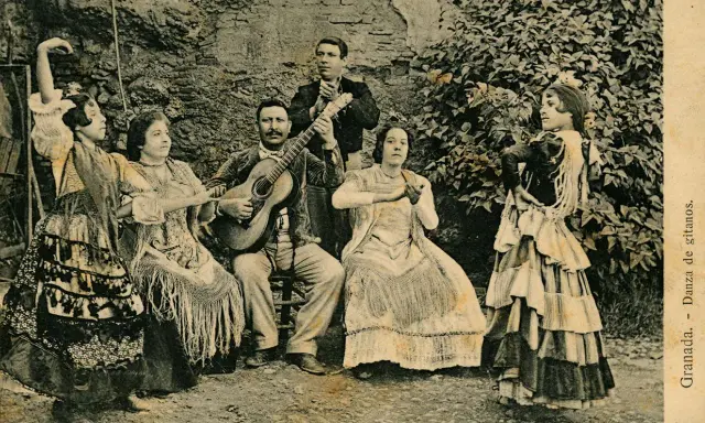 Grupo de músicos y bailarinas, una de ellas realiza un zambra baile gitano, con guitarras y mantones.