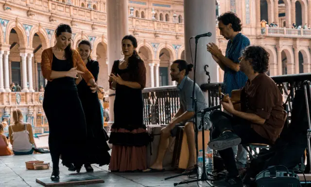 Artistas flamencos crean un jaleo de música y baile en una plaza.