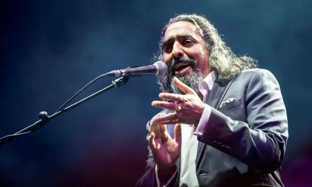 Un cantaor gitano, con su voz profunda y gestos apasionados, cautiva al público en el escenario.