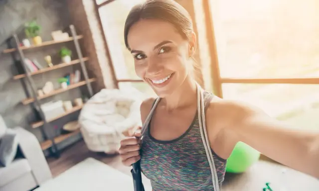Sonriendo mujer con cuerda de saltar, lista para disfrutar los beneficios de saltar a la comba.