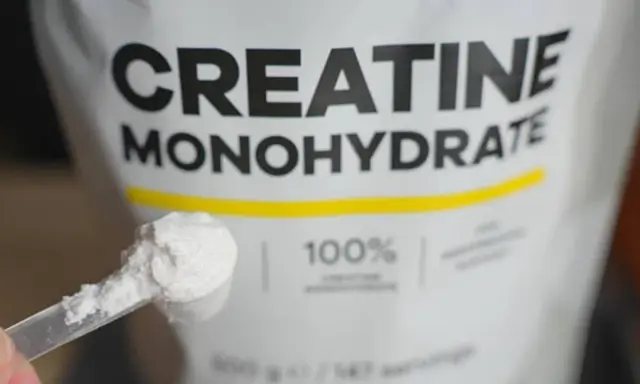Bolsa de creatina monohidrato con una cuchara llena de polvo blanco. Ideal para potenciar tus músculos.