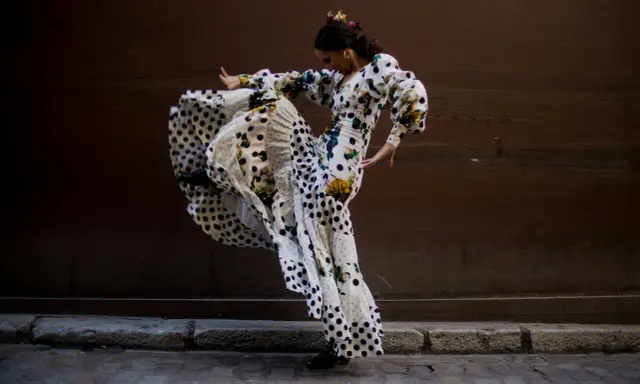 Bailarina de flamenco con vestido de lunares y volantes, capturando la esencia del flamenco origine en un movimiento apasionado.